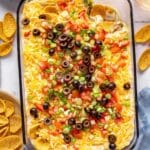 7-layer dip topped with black olives, green onions and diced tomatoes with Fritos dipped in.