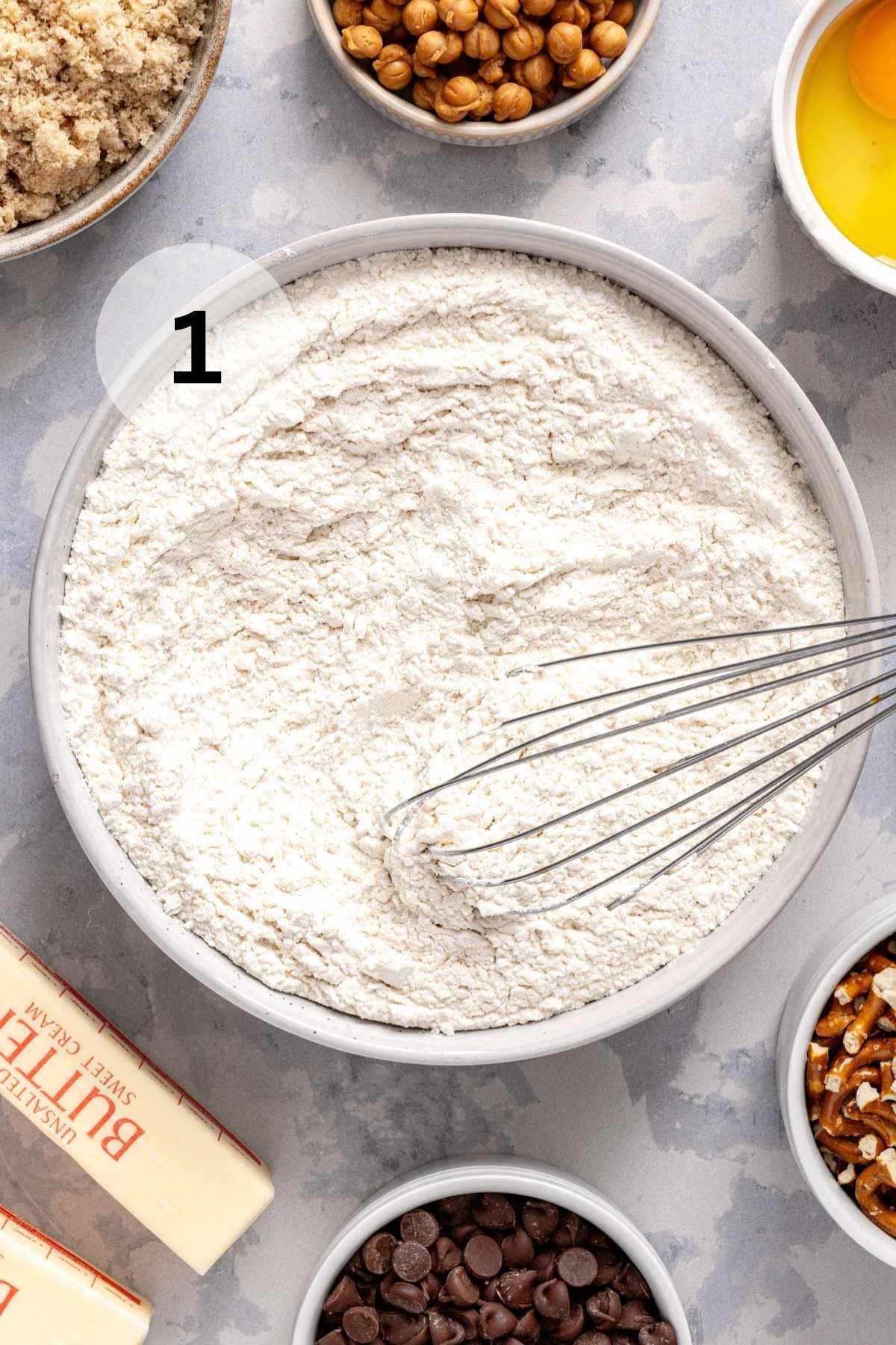 Whisking flour with other dry ingredients in a large bowl.