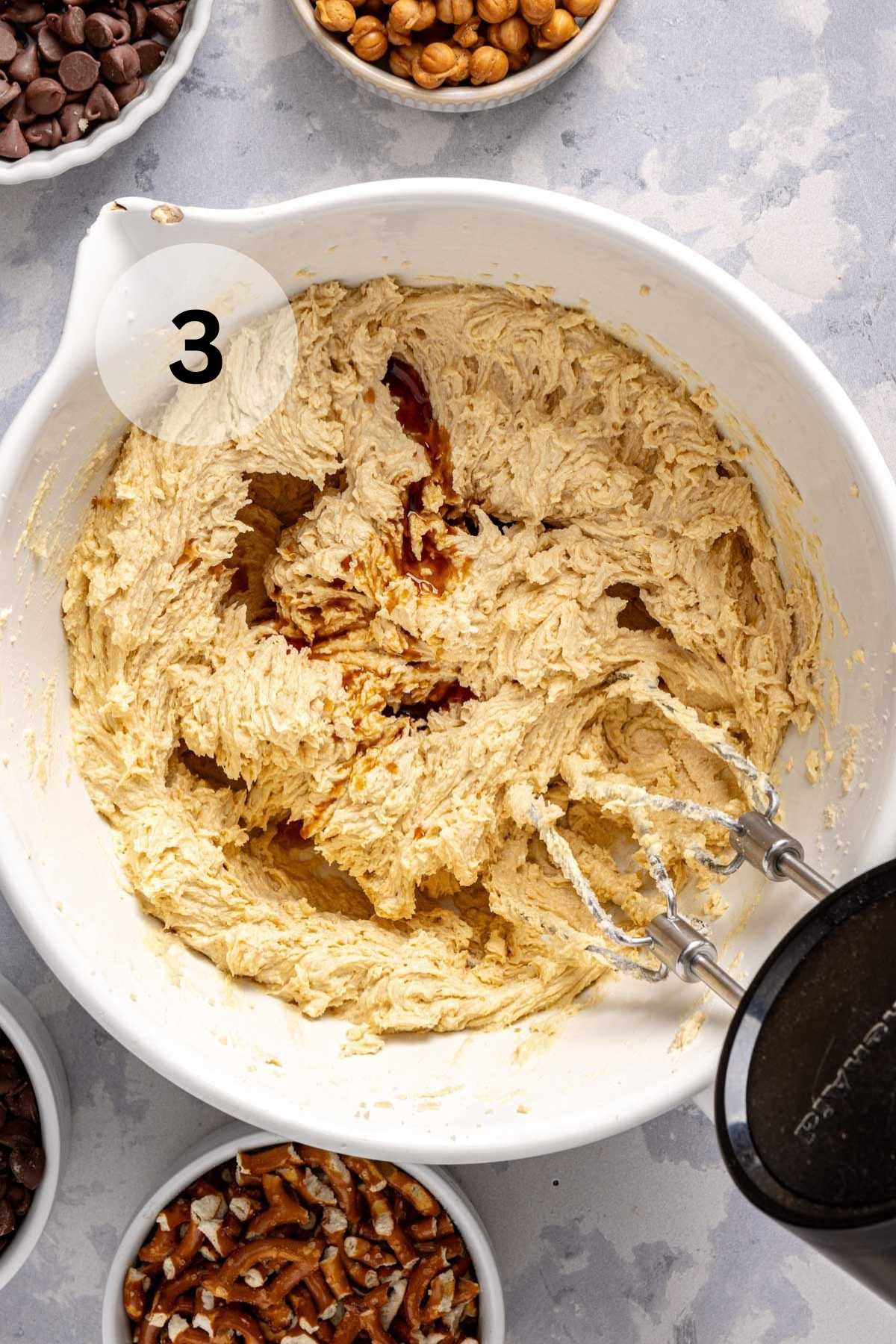 Using a mixer to beat in eggs and vanilla to cookie batter.