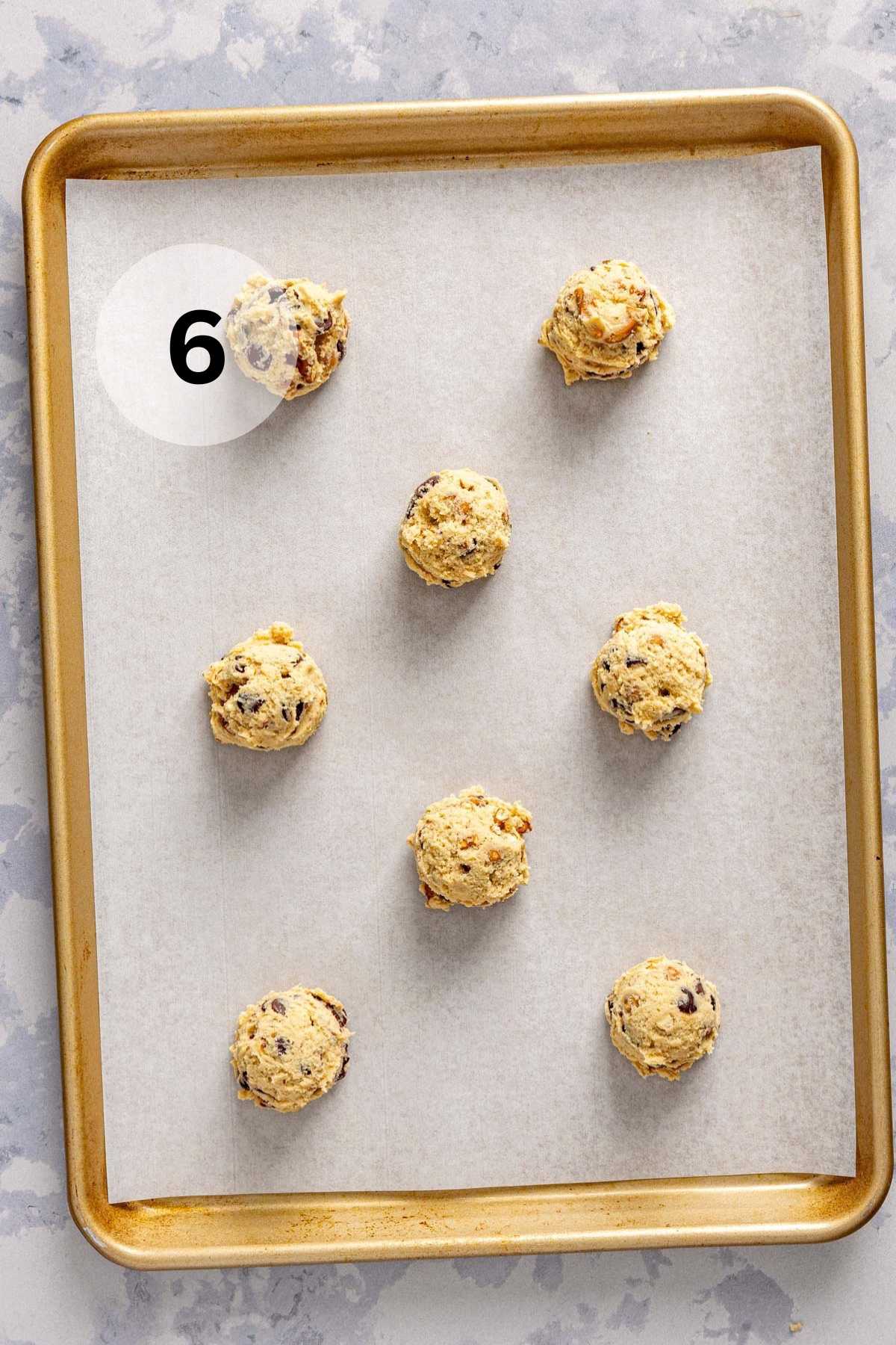 Cookie dough balls on a parchment lined cookie sheet pan.