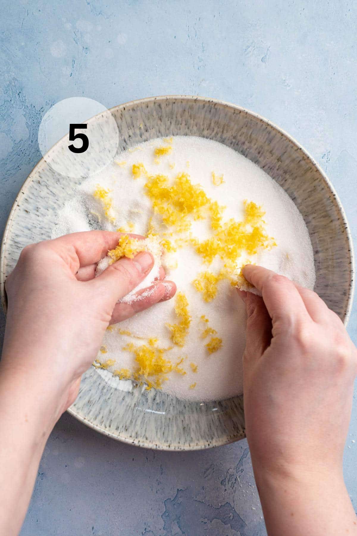 Hands mixing lemon zest into sugar.