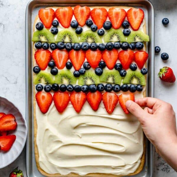 Topping a cookie crust with sliced fresh strawberries.