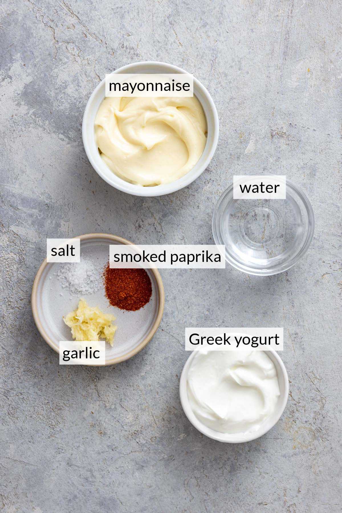 Small bowls with mayonnaise, Greek yogurt, paprika, water and garlic.