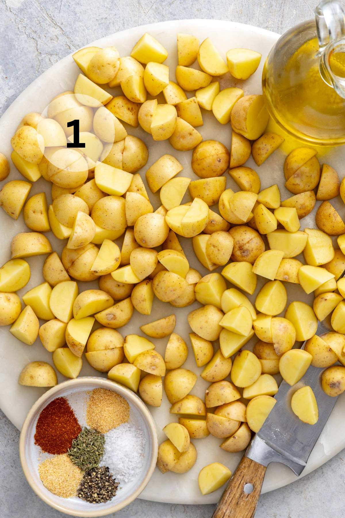 Diced Yukon gold potatoes on a plate near spices and a jar of oil.