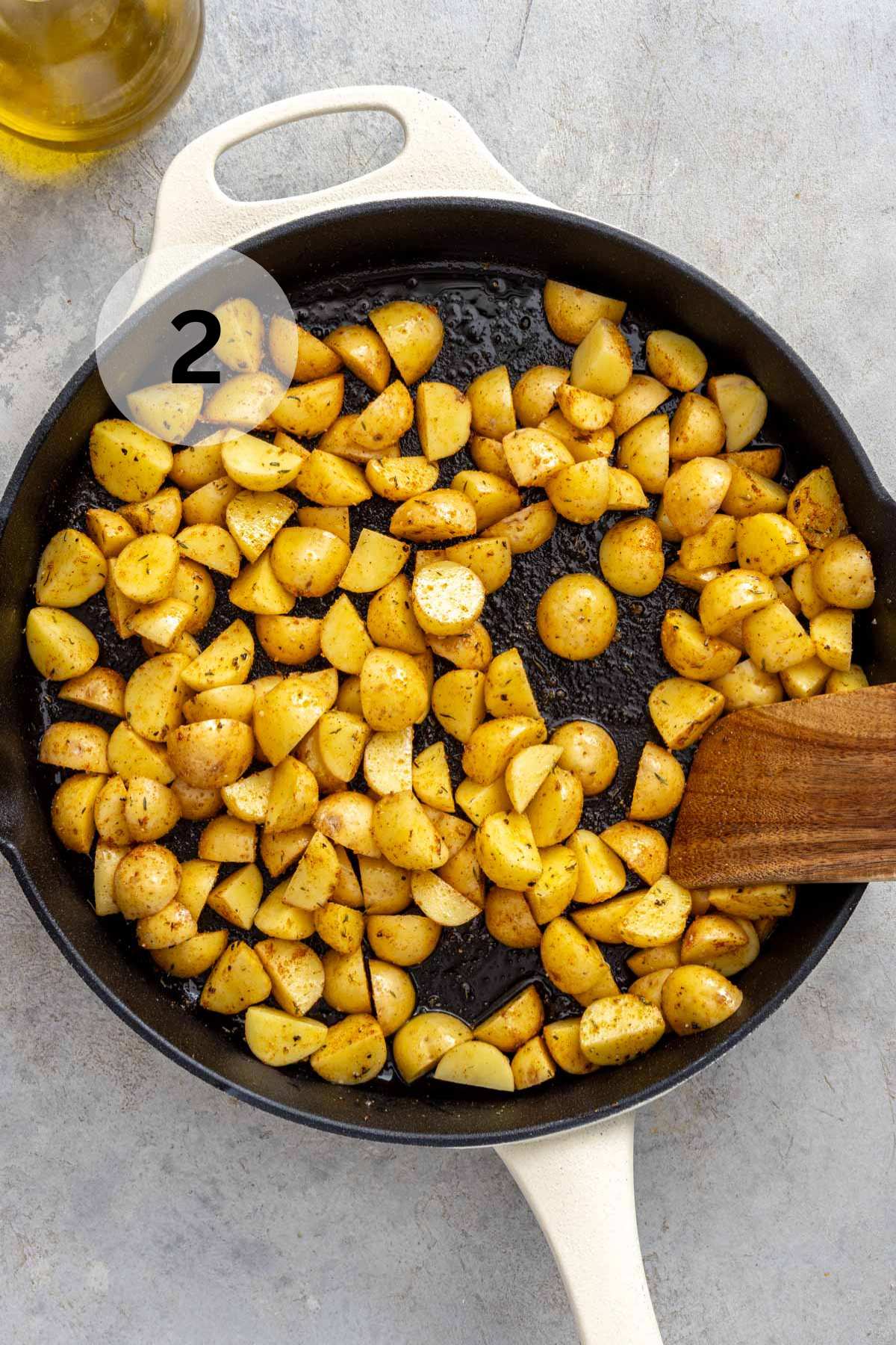 Stirring cubed potatoes in an iron skillet.