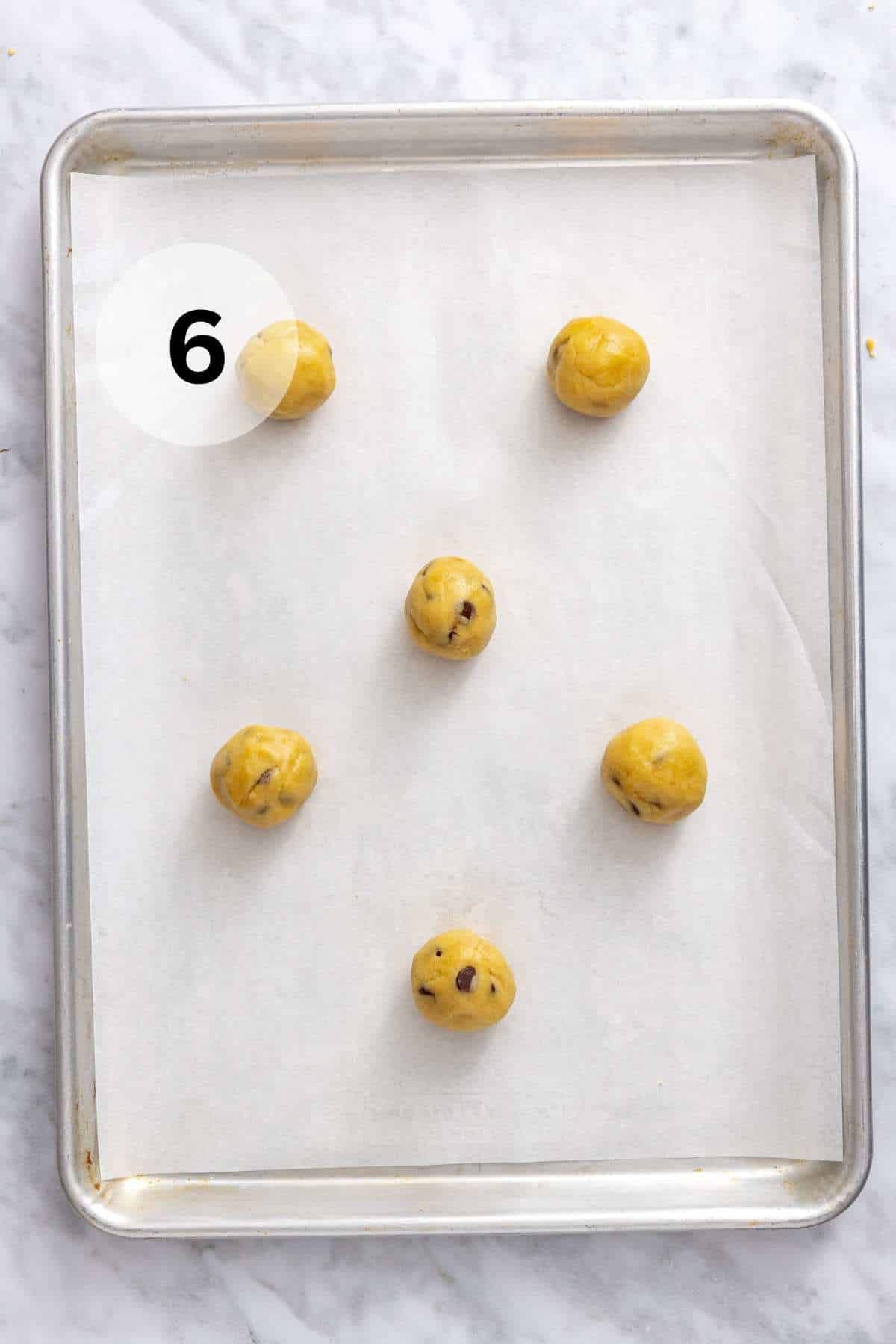 Cookie dough balls on a parchment-lined cookie sheet.
