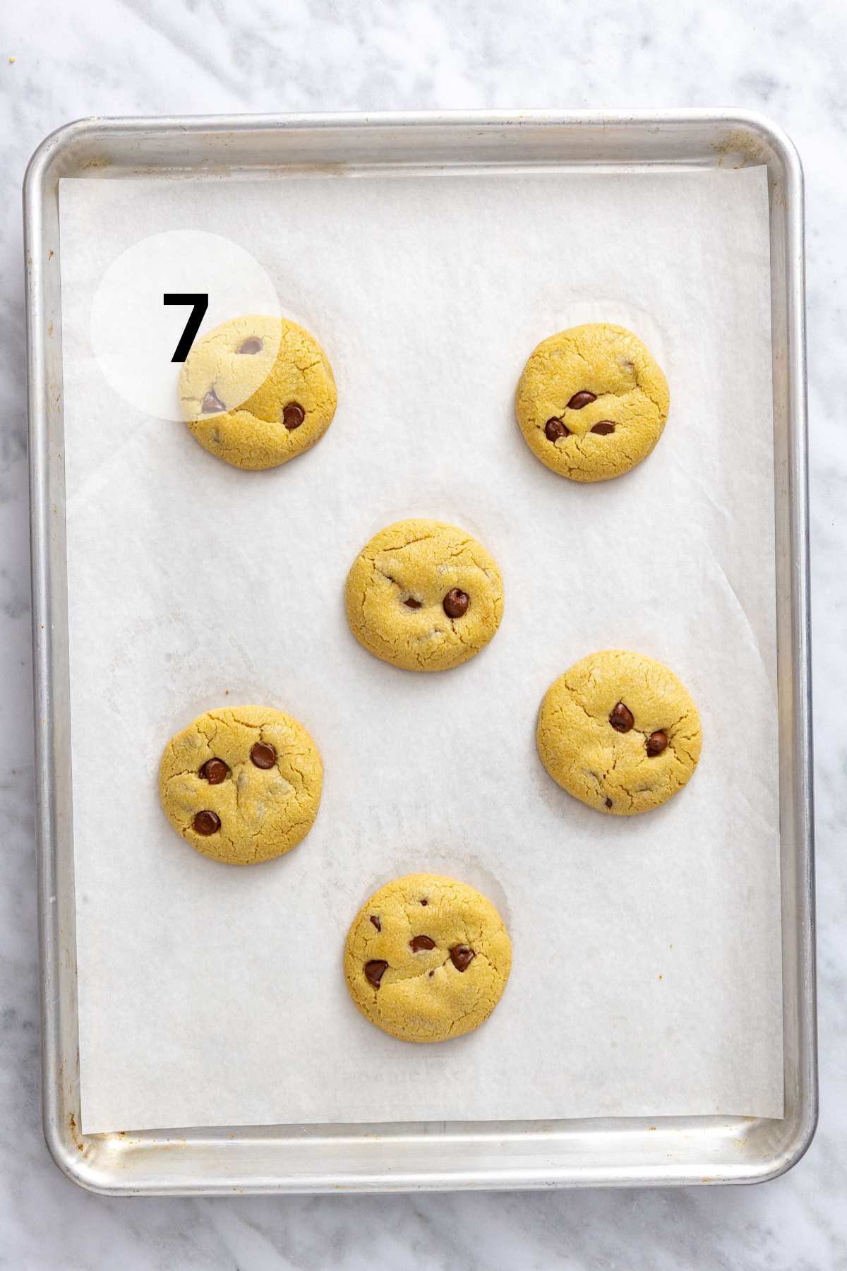 Baked chocolate chip cookies on a sheet pan.