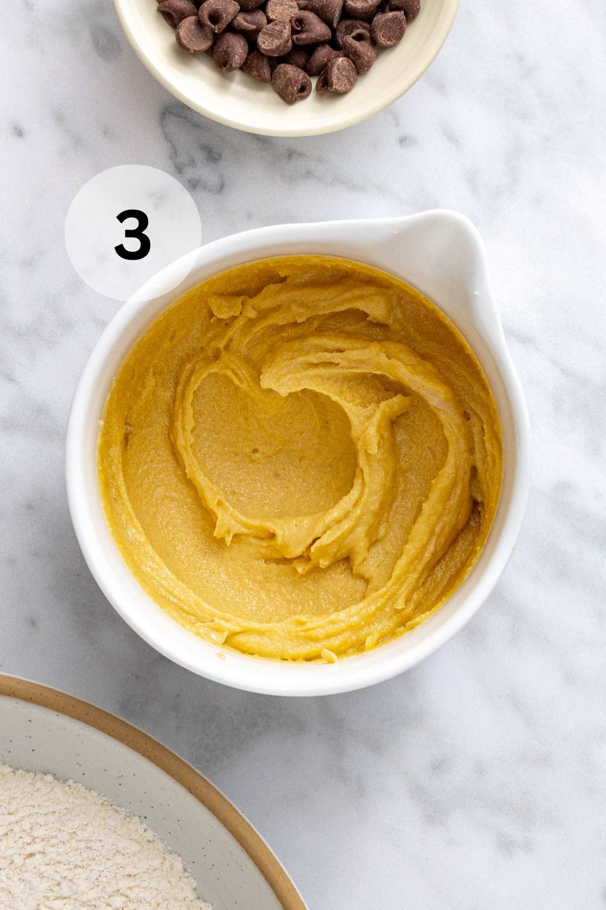 Egg yolk, butter and sugars mixed in a white mixing bowl.