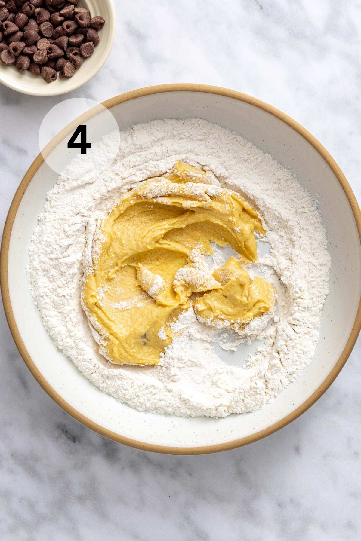 Mixing the wet ingredients with the flour mixture in a bowl.