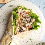 Greek chicken salad in a wrap served on a plate.