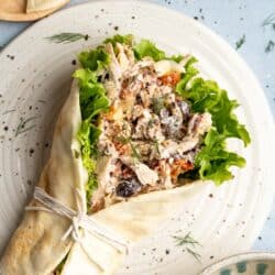 Greek chicken salad in a wrap served on a plate.