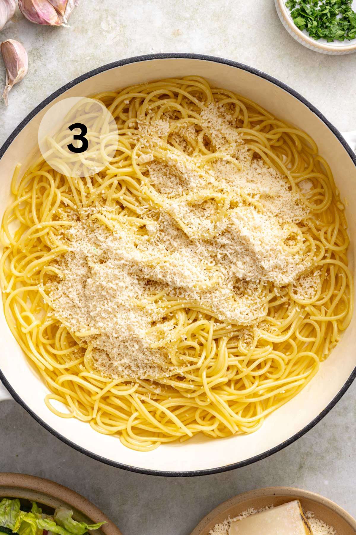 Parmesan cheese sprinkled over buttered noodles in a pot.