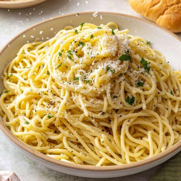 Sprinkling parmesan cheese over buttered noodles.