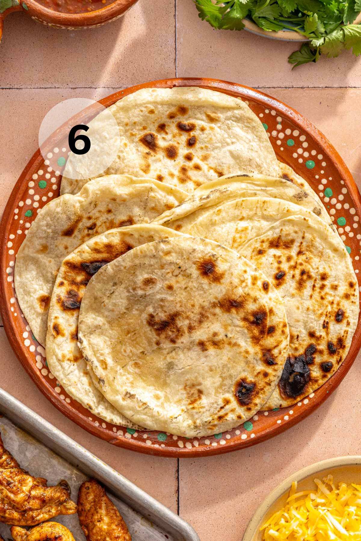 Charred flour tortillas on a large plate.