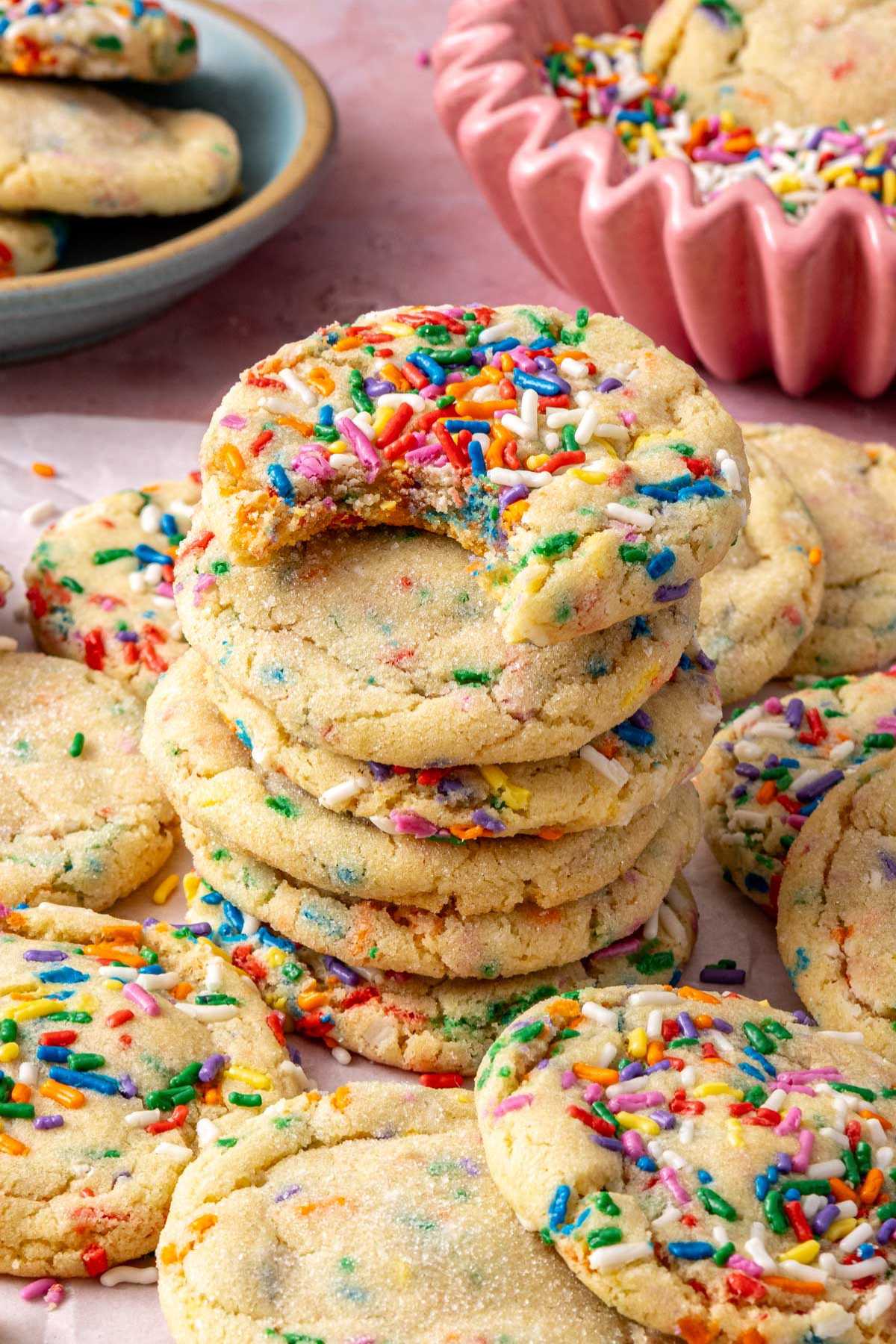 Stacked sprinkle cookies with a bite taken out of one.