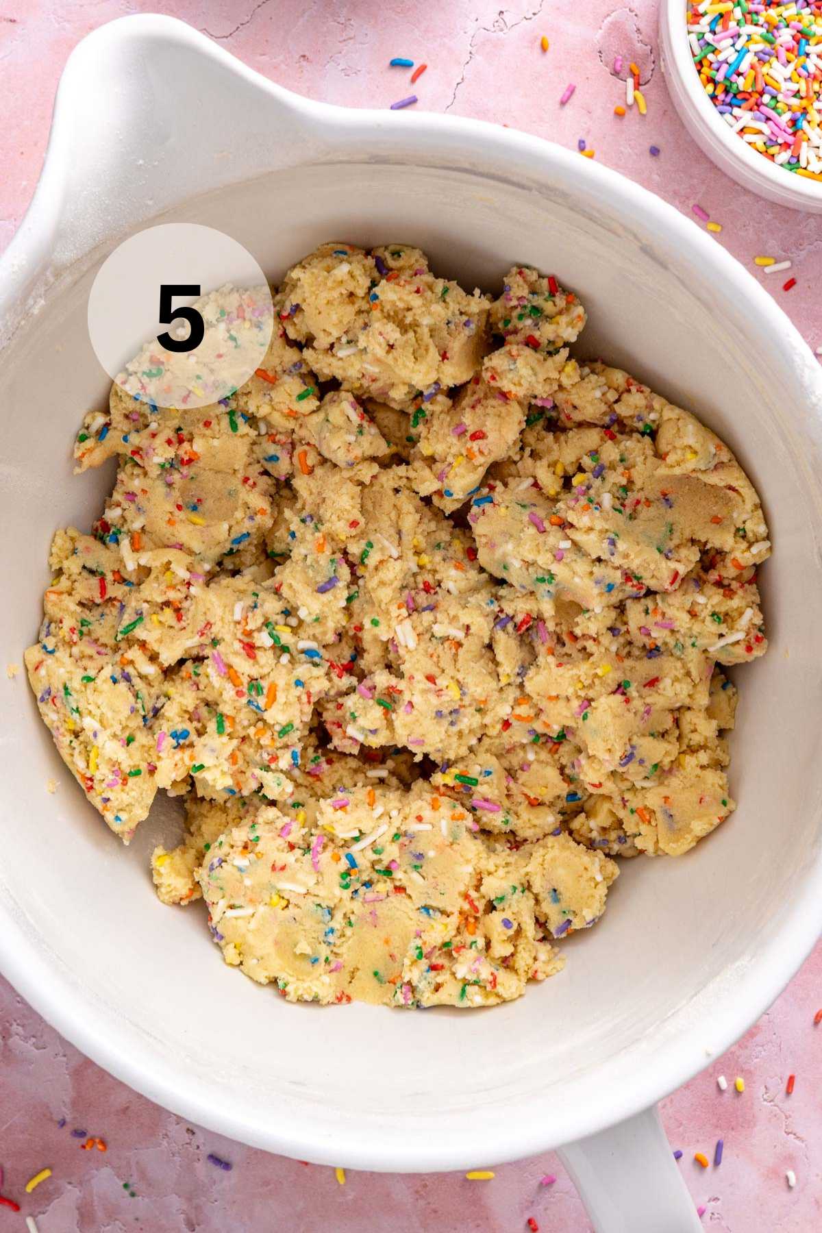 Cookie dough with sprinkles in a white bowl.