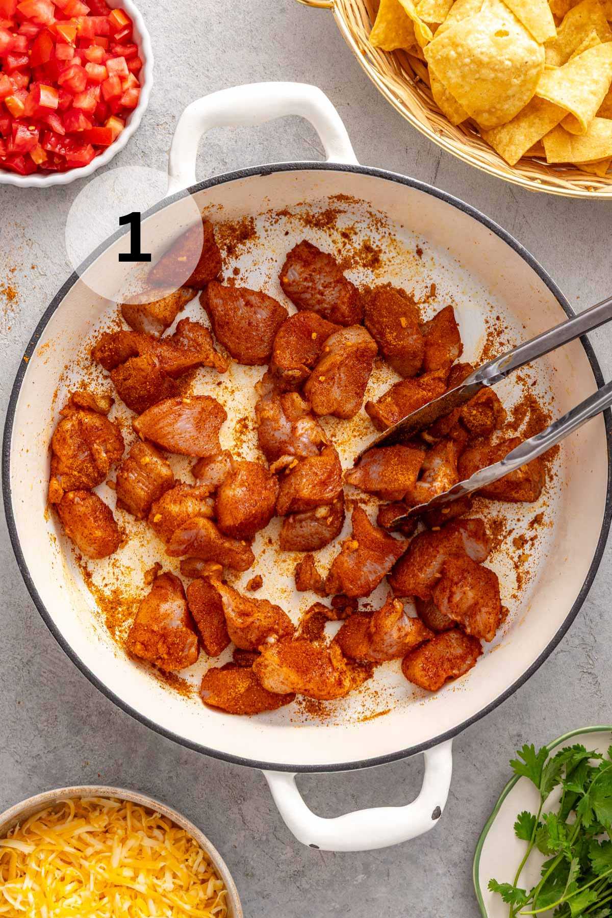 Tossing pieces of chicken in taco seasoning.