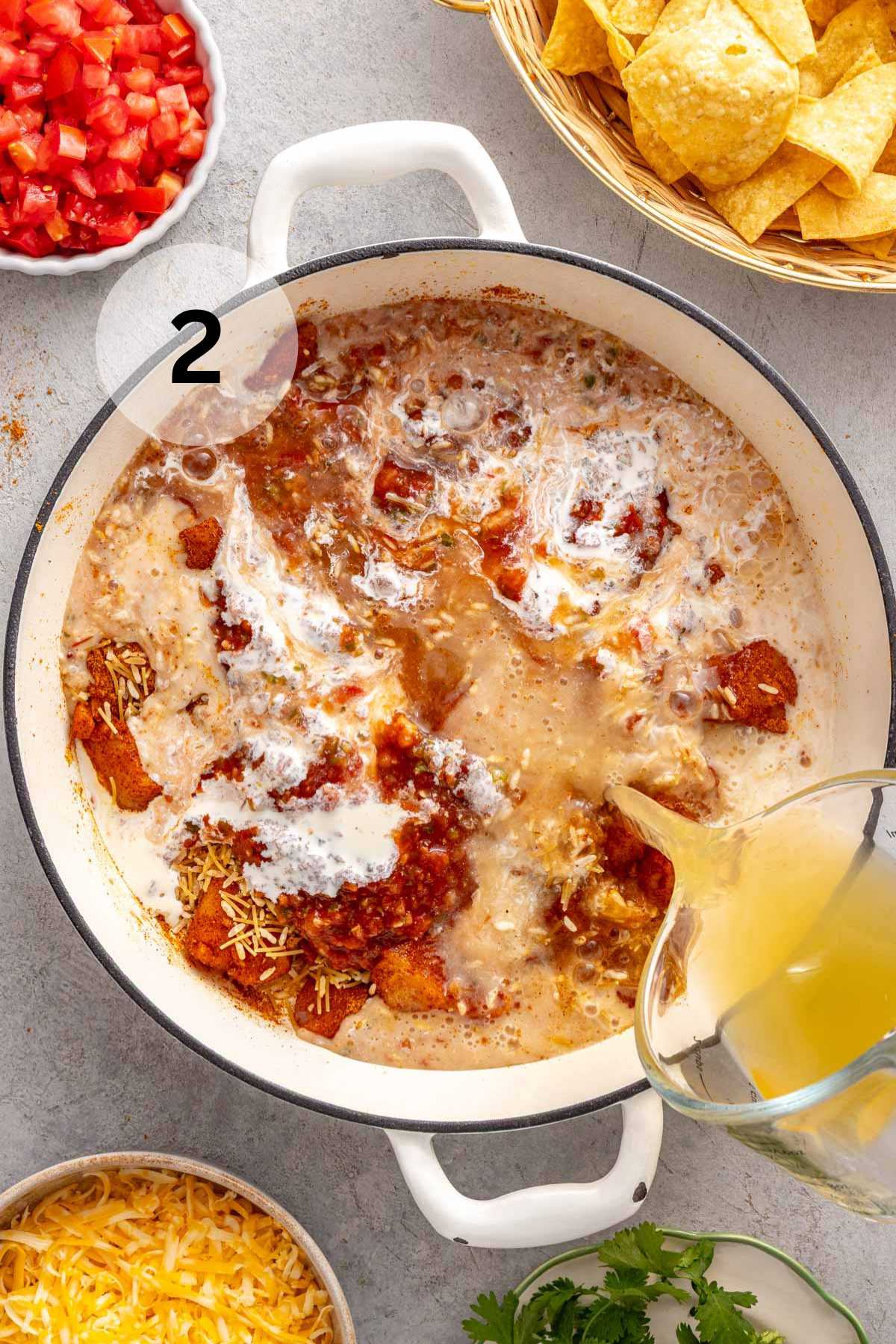 Pouring chicken broth into a pot with chicken, rice, and cream.