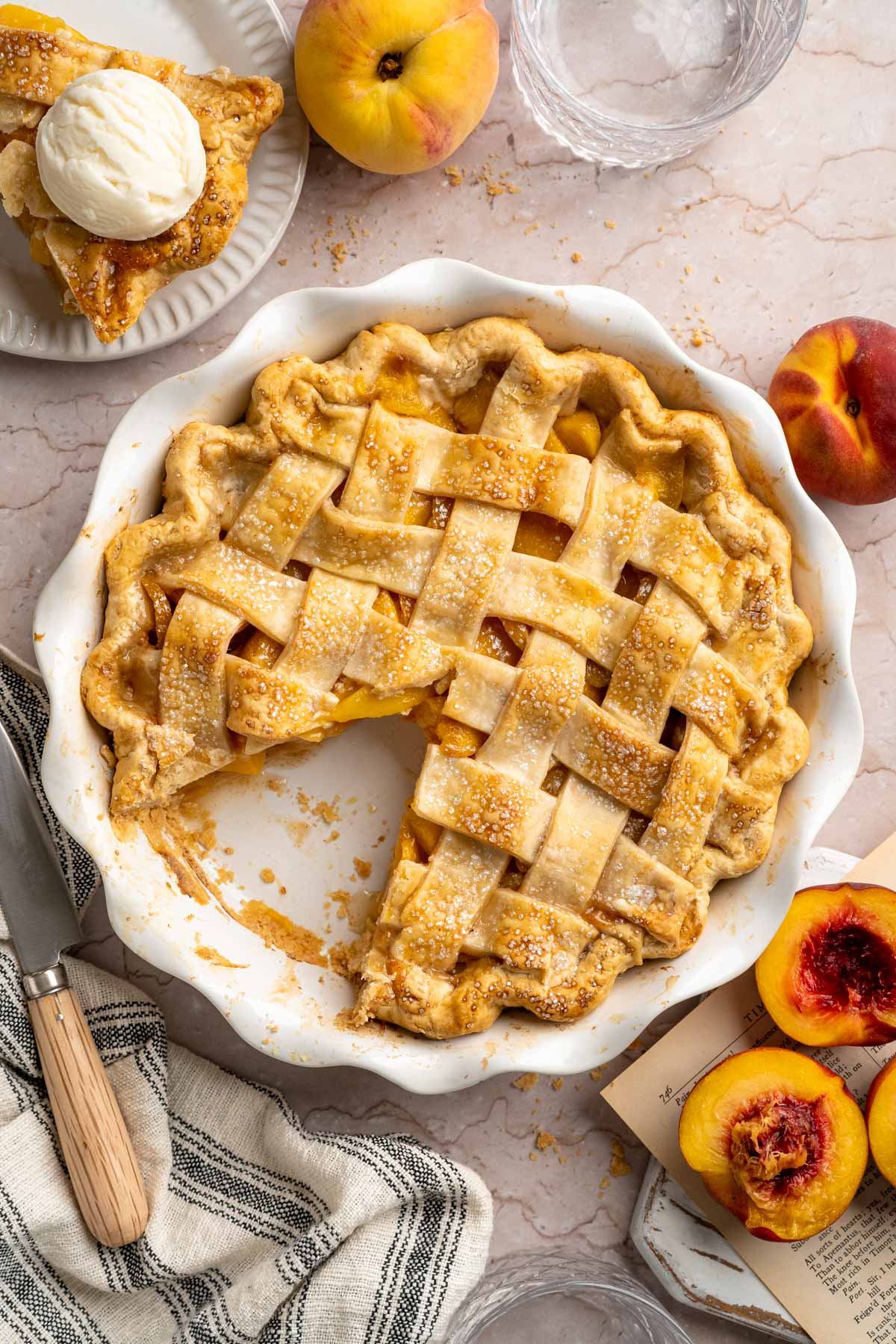 Peach pie in a white pie plate with one piece missing.
