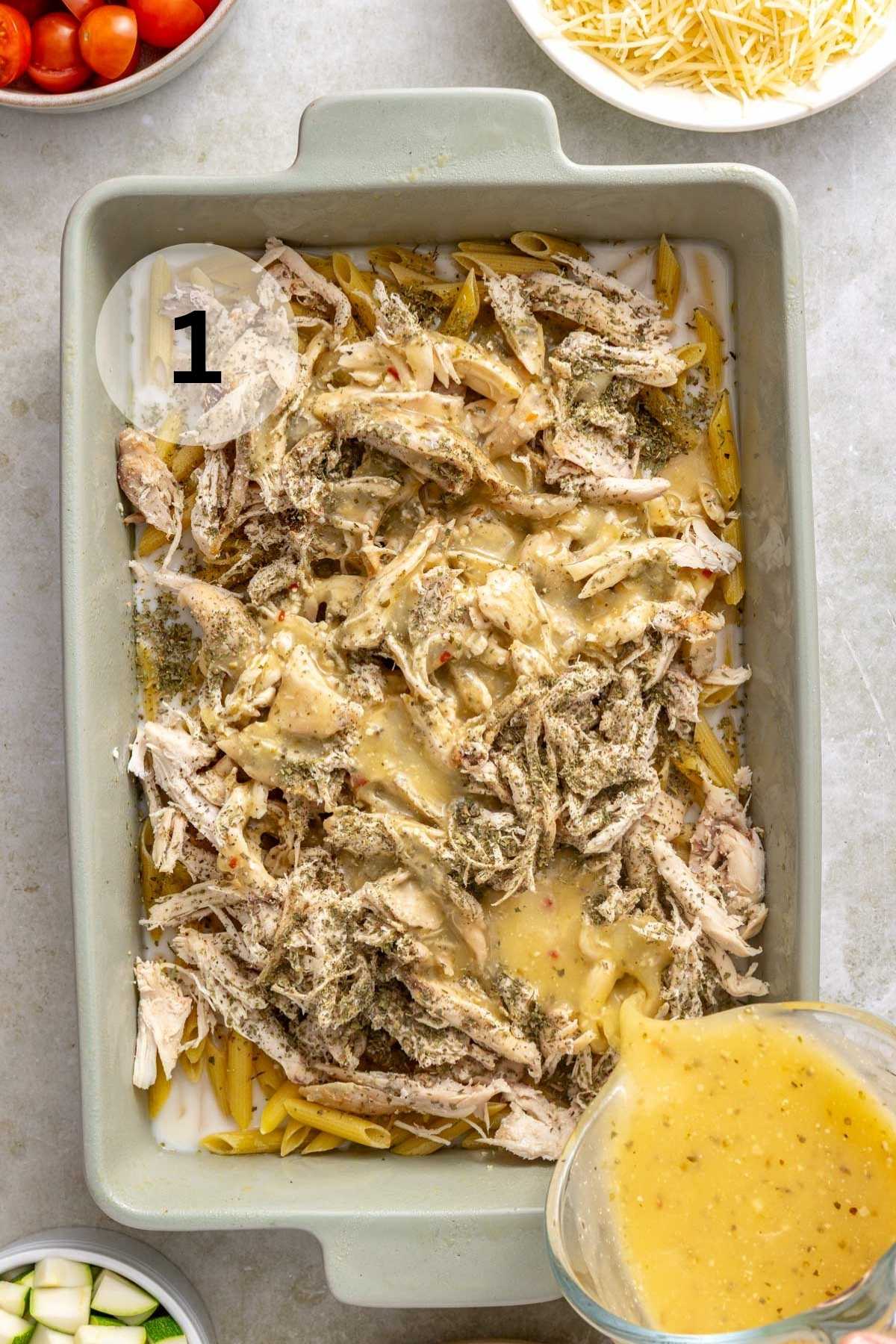 Pouring Italian dressing in a dish with shredded chicken and pasta.