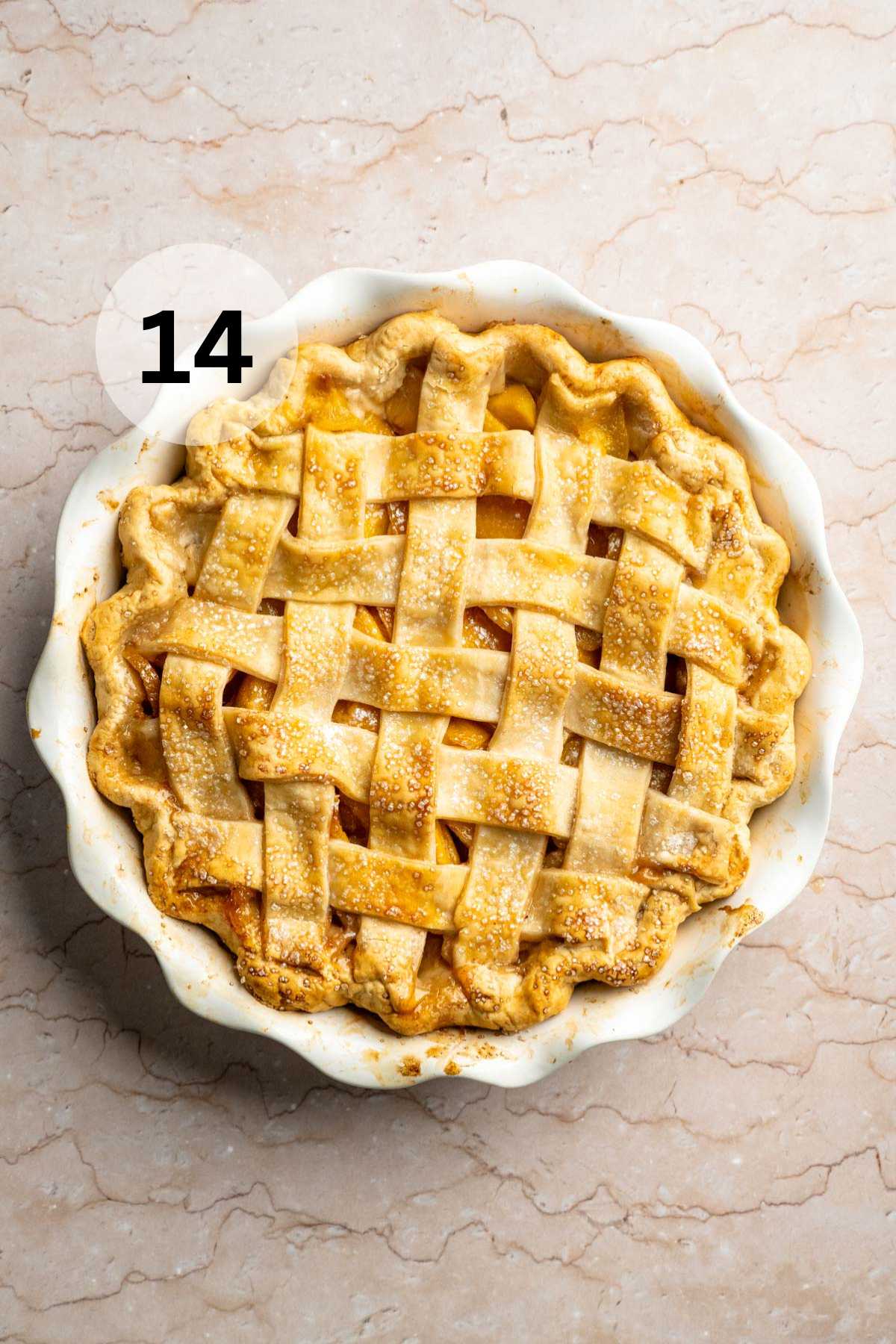 Peach pie with a lattice crust in a white pie plate.
