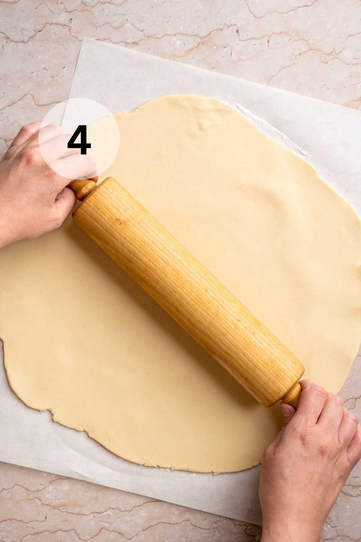 Using rolling pin to roll out crust on parchment paper.