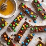 Homemade protein bars topped with a layer of chocolate and M&M's.