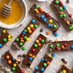 Homemade protein bars topped with a layer of chocolate and M&M's.