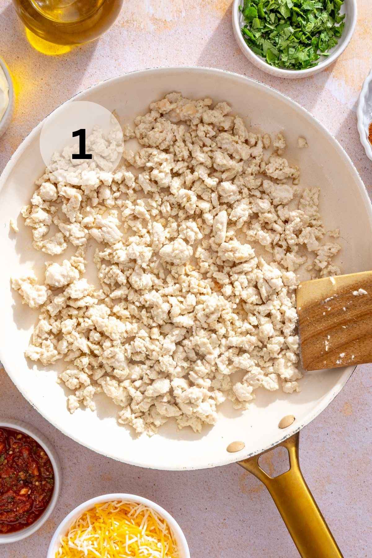 Cooking ground chicken in a skillet.