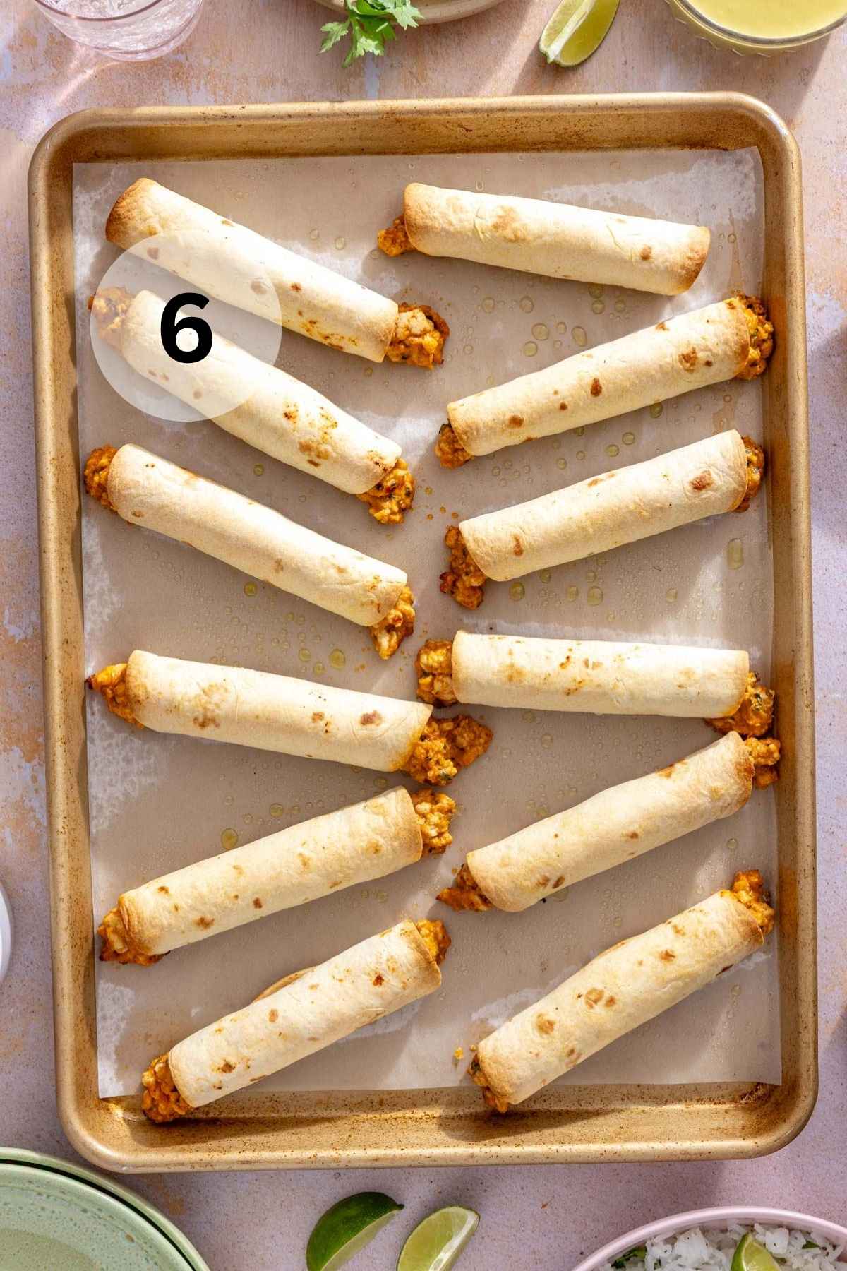 Baked chicken taquitos on a cookie sheet.