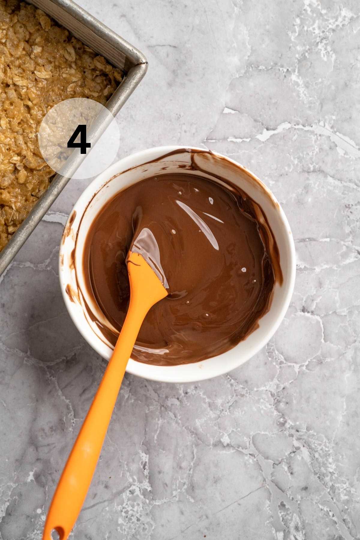 Stirring melted chocolate in a small bowl.