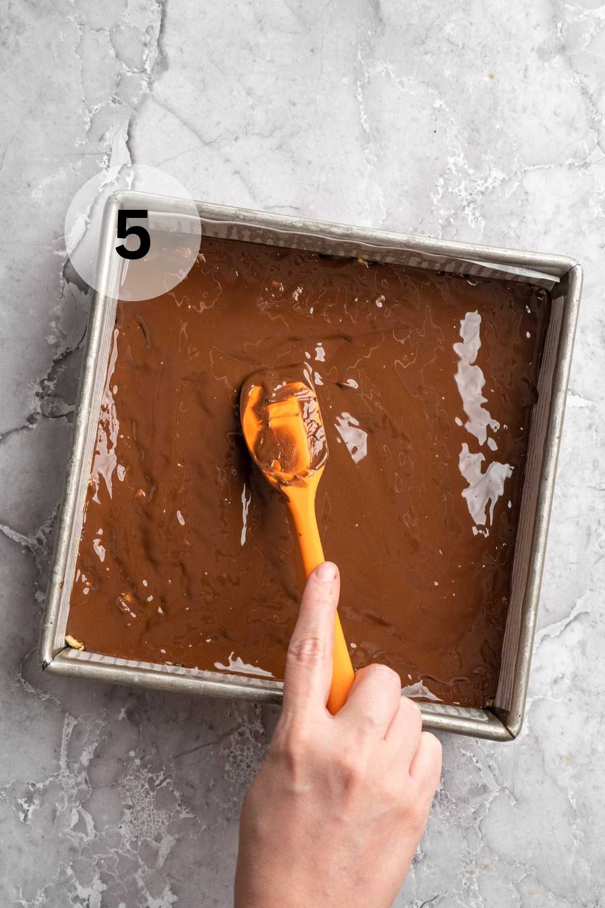 Spreading melted chocolate over protein bars.
