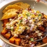 Squeezing lime over a sweet potato ground beef bowl with street corn.