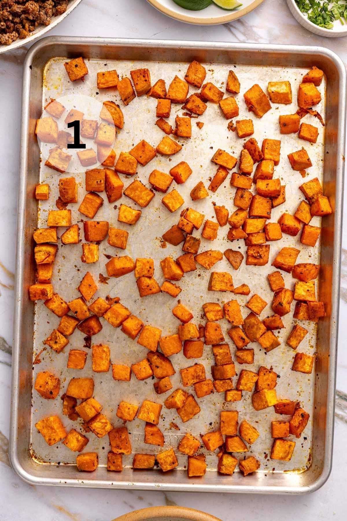 Roasted cubed sweet potato on a sheet pan.