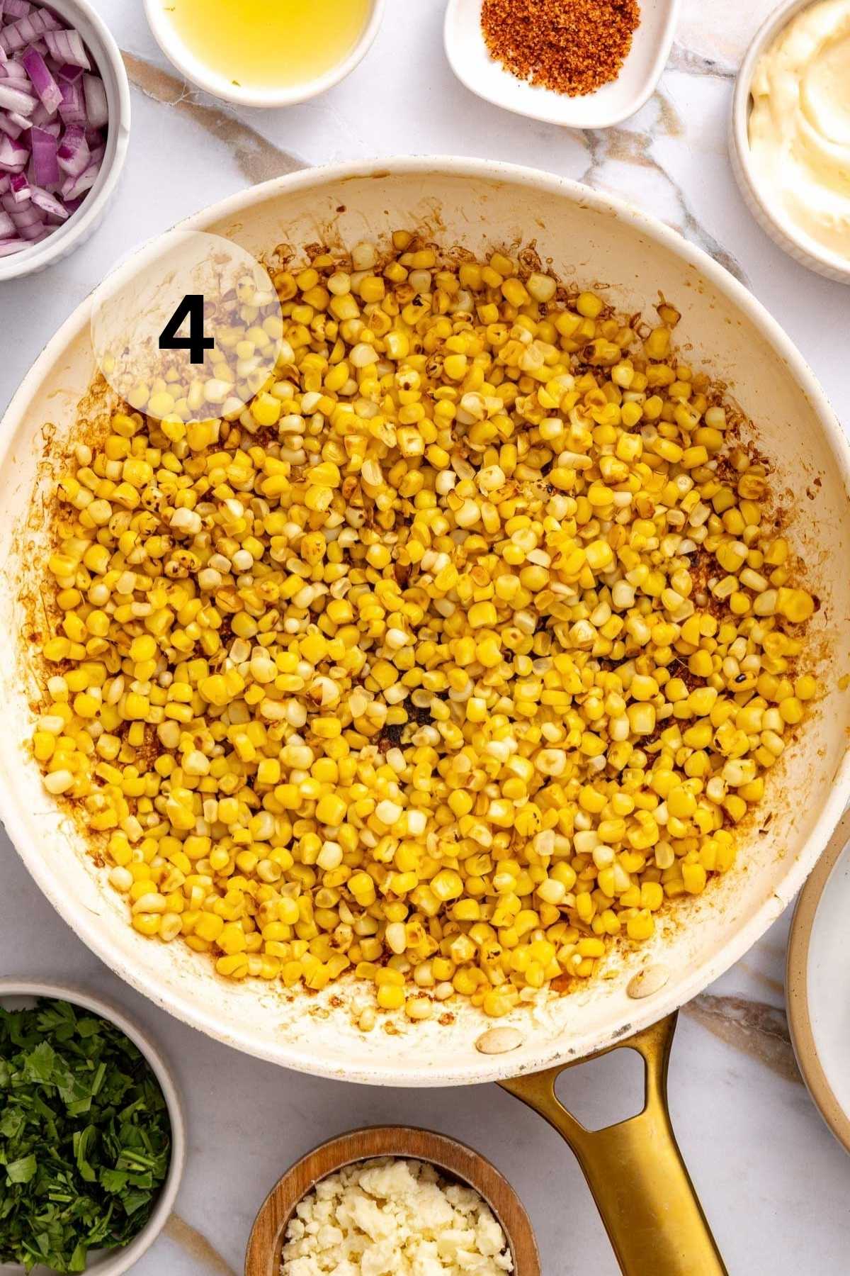 Charred corn in a white skillet.
