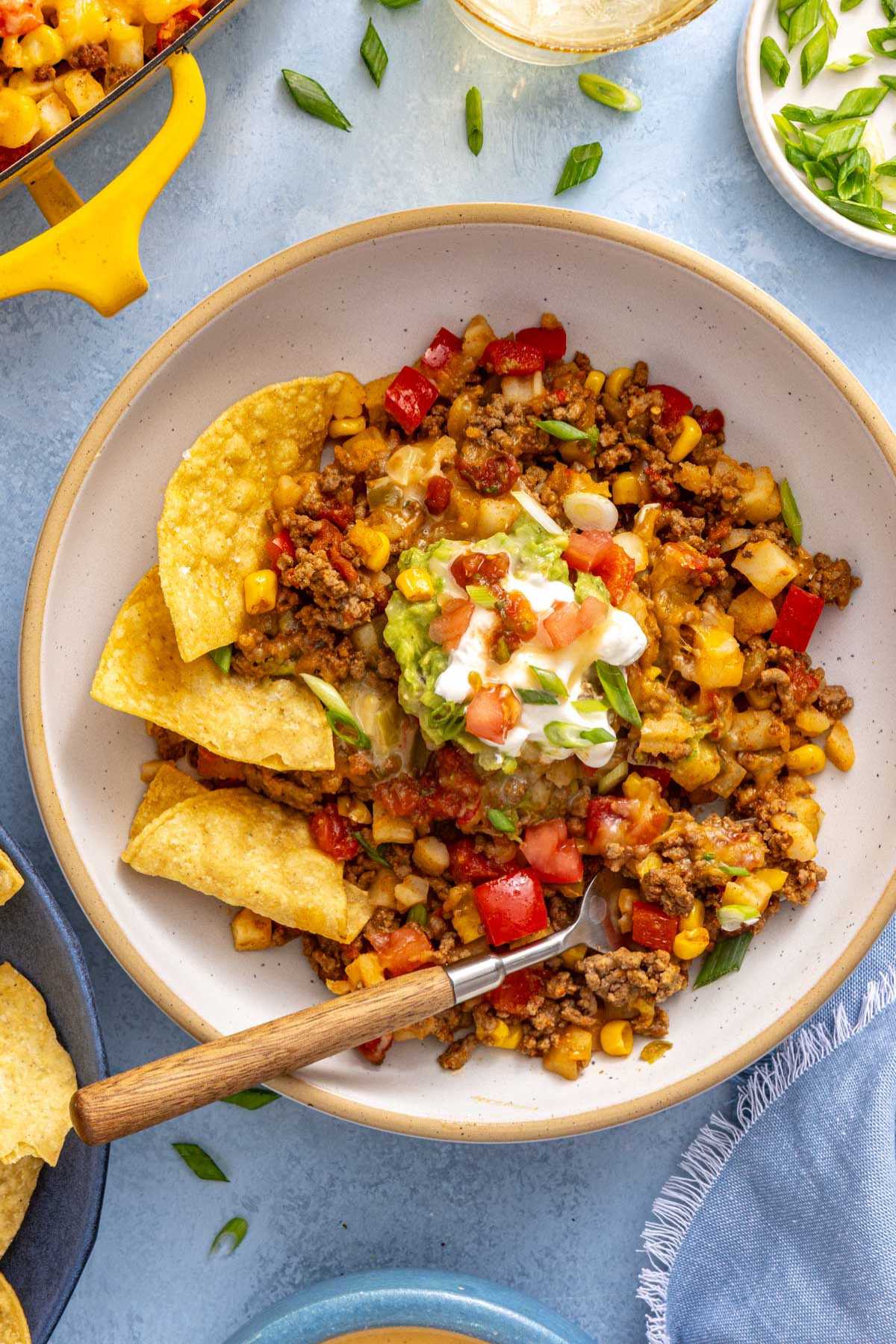 Taco potatoes served in a bowl with guacamole, sour cream and tortilla chips.
