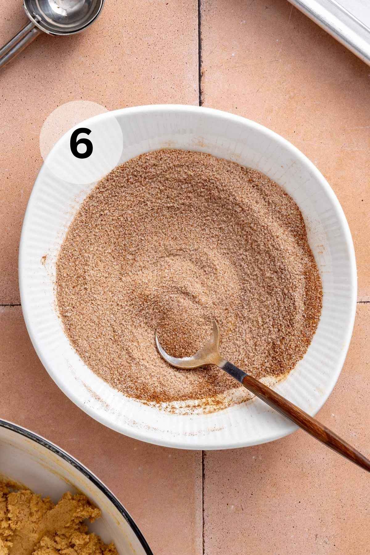 Stirring cinnamon and sugar together in a small bowl.