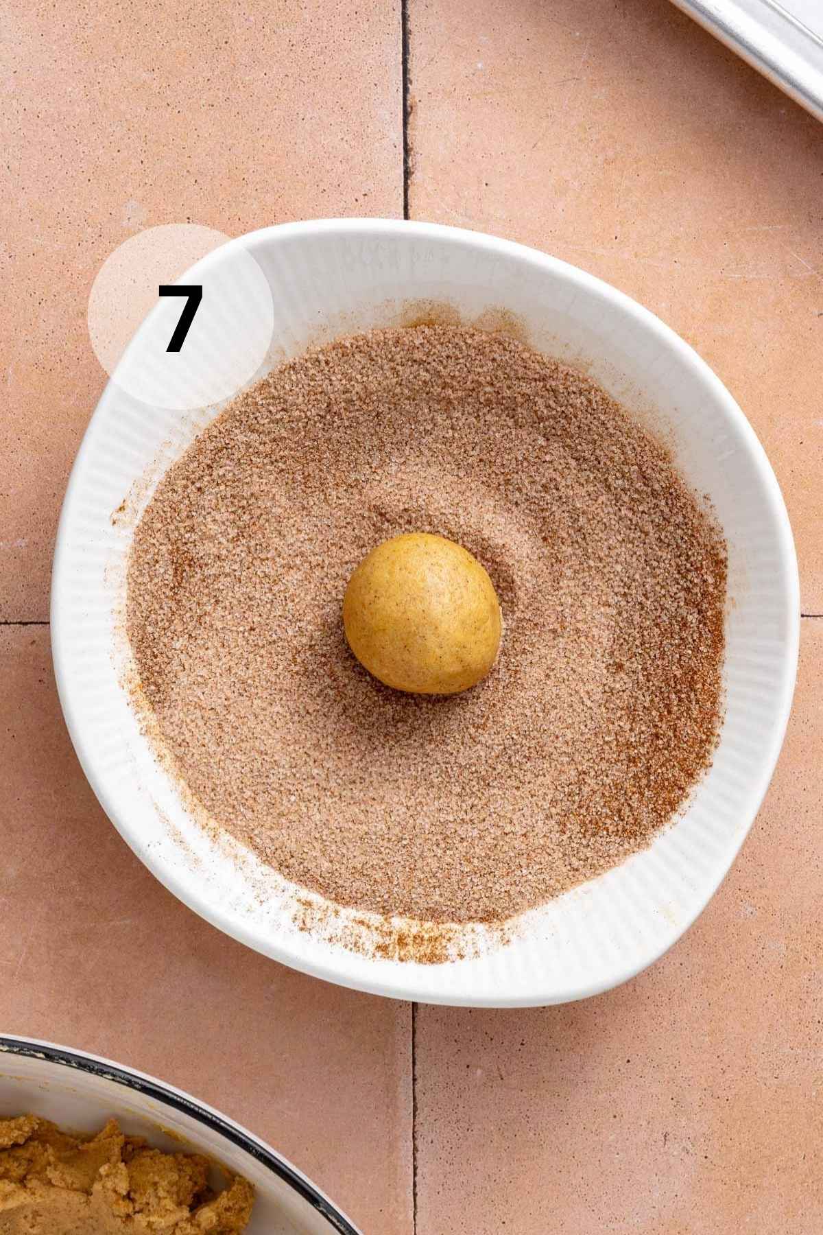 Rolling a cookie dough ball in cinnamon and sugar mixture.